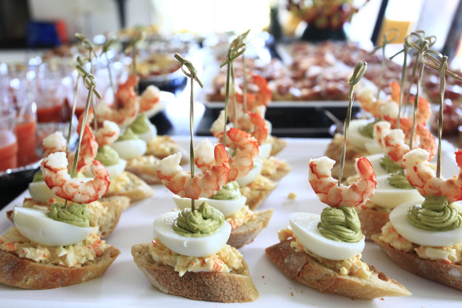Prawn and egg pintxos on toothpicks lined up on a tray