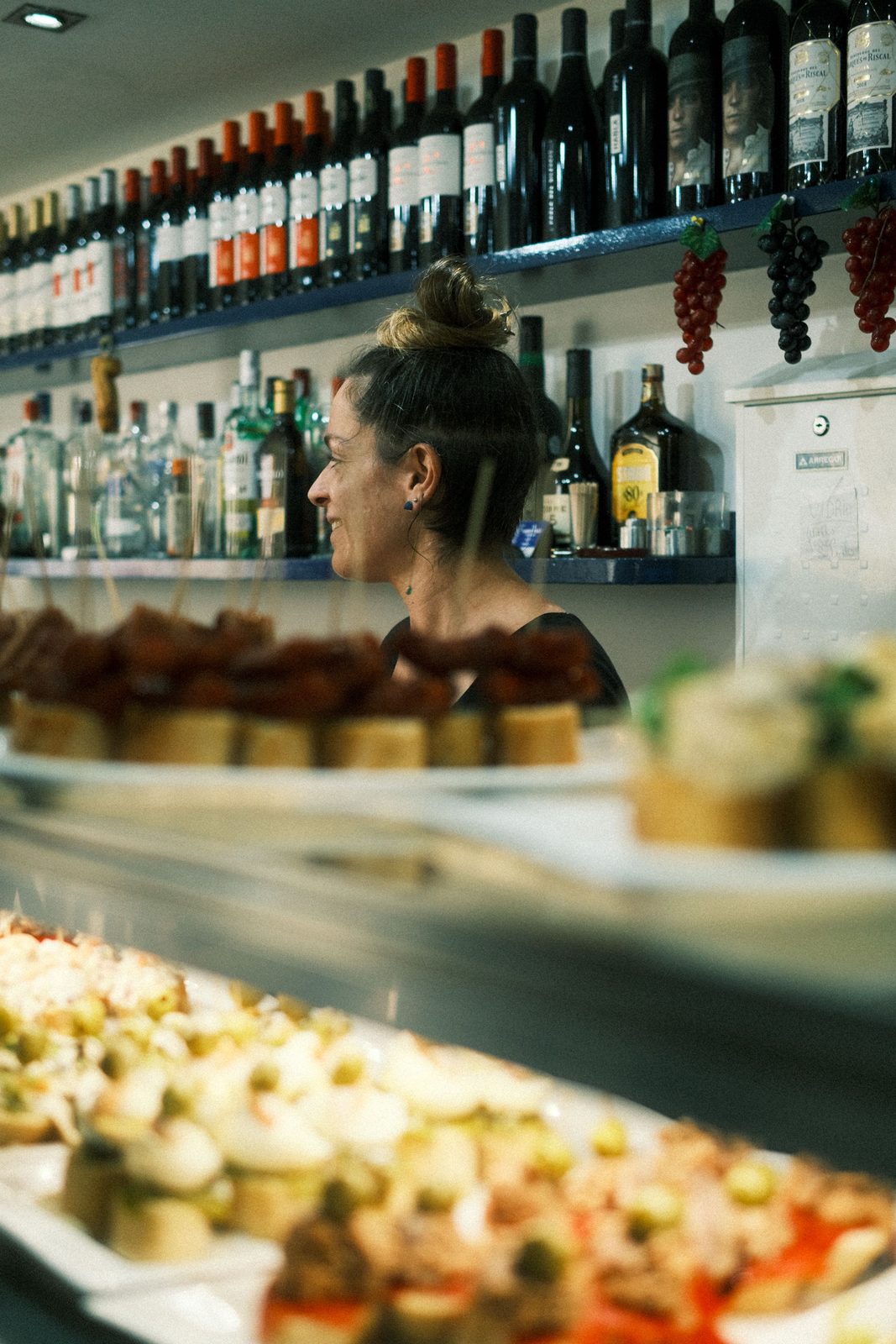A bartender behind a pintxo counter lined with plates in San Sebastián