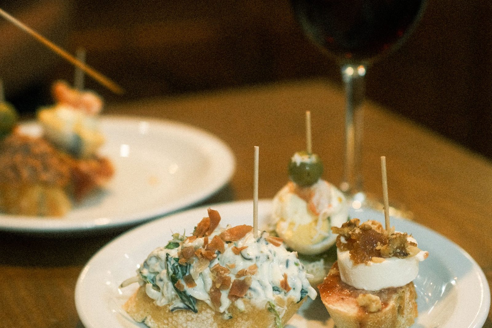 Pintxos on a plate with a glass of red wine at a San Sebastián bar