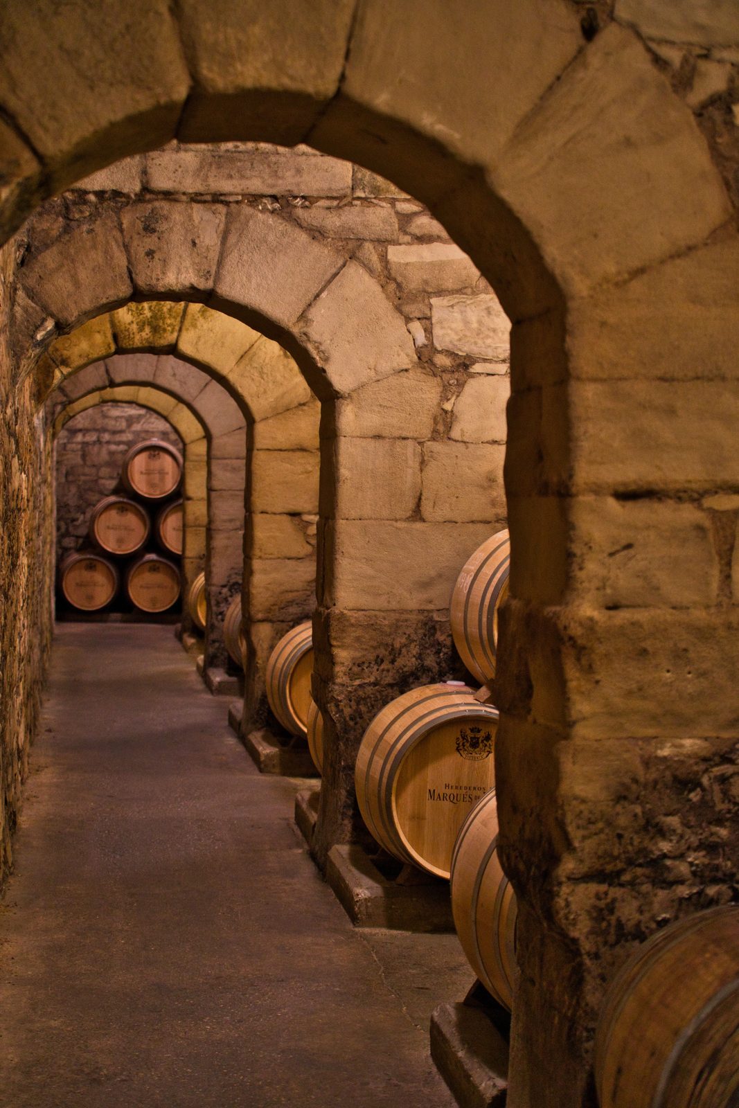 Stone arches and oak barrels in an underground Rioja cellar
