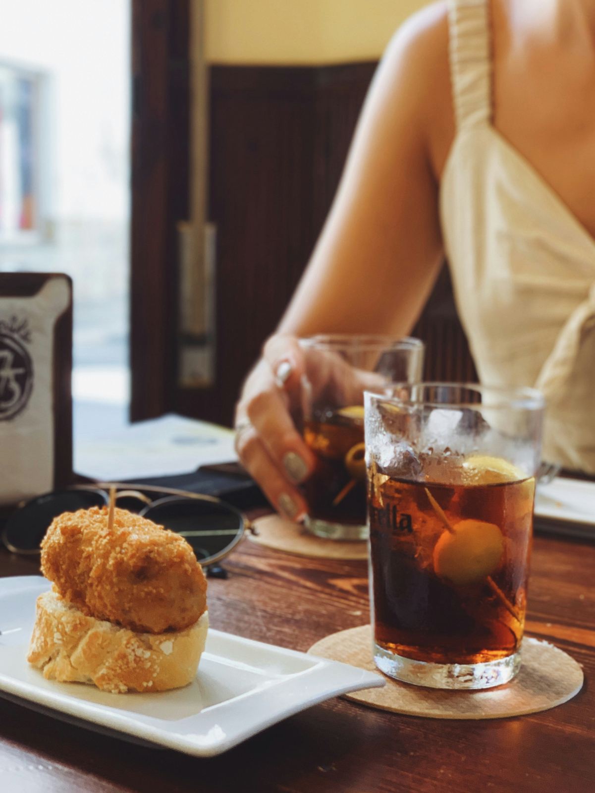 Vermut on ice with an olive beside a croqueta at a Barcelona bar counter